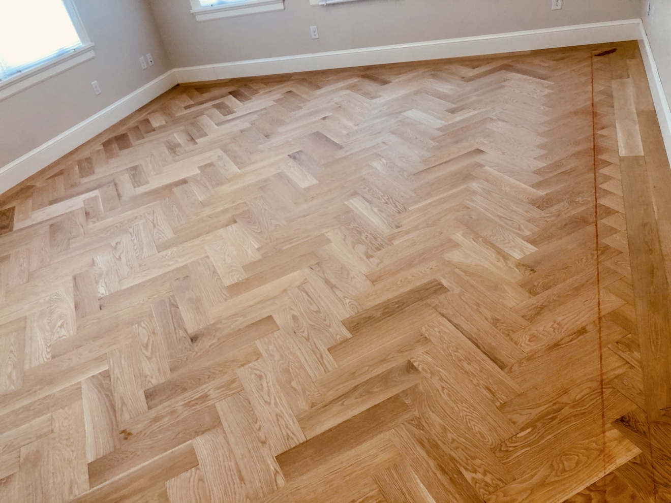 Custom herringbone wood floor framed by a fitted perimeter border