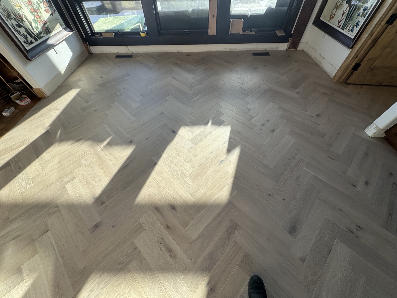Custom herringbone wood flooring installed at a bright residential entry