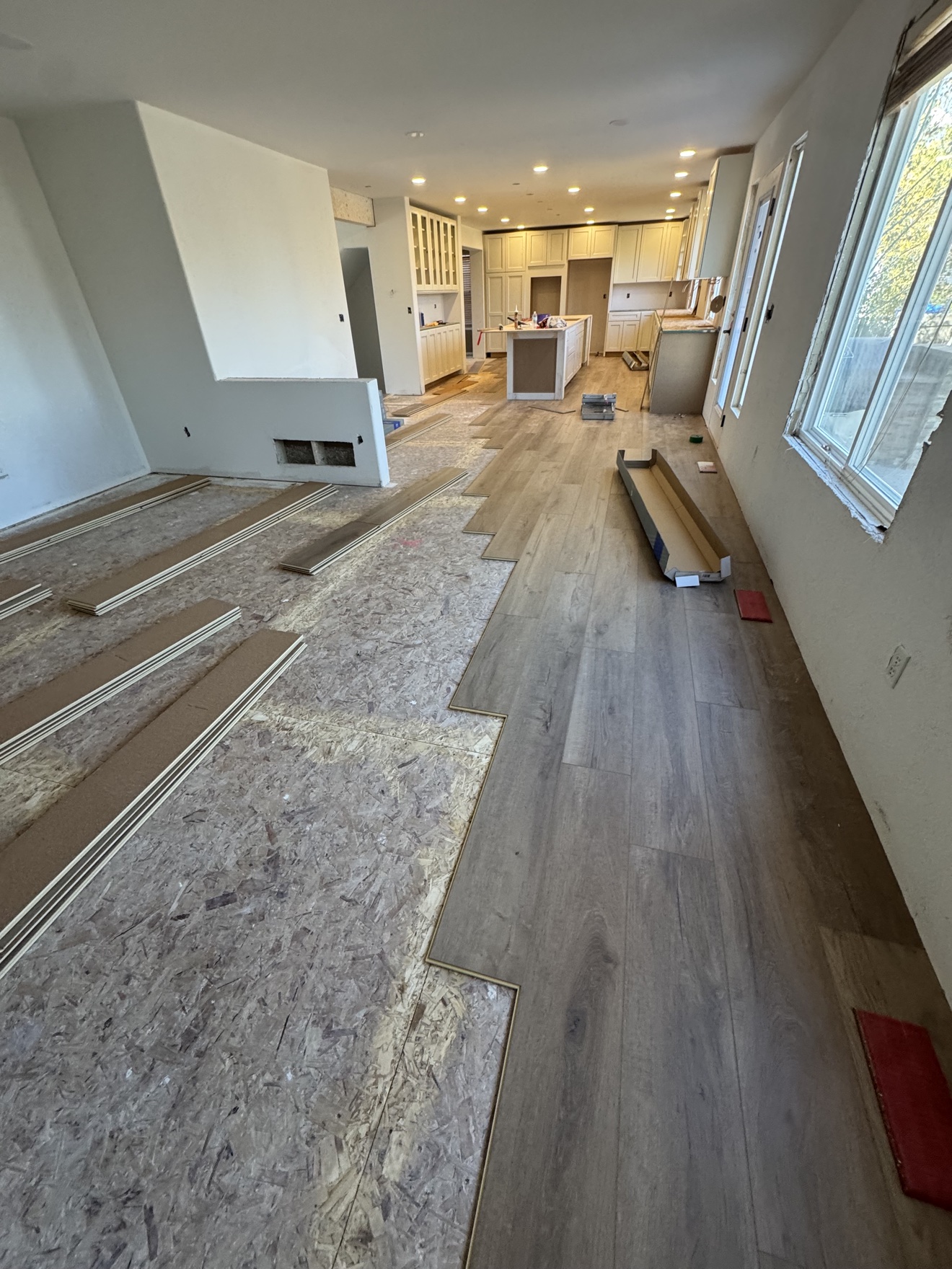 Luxury vinyl plank installation in progress across an open-plan residential interior