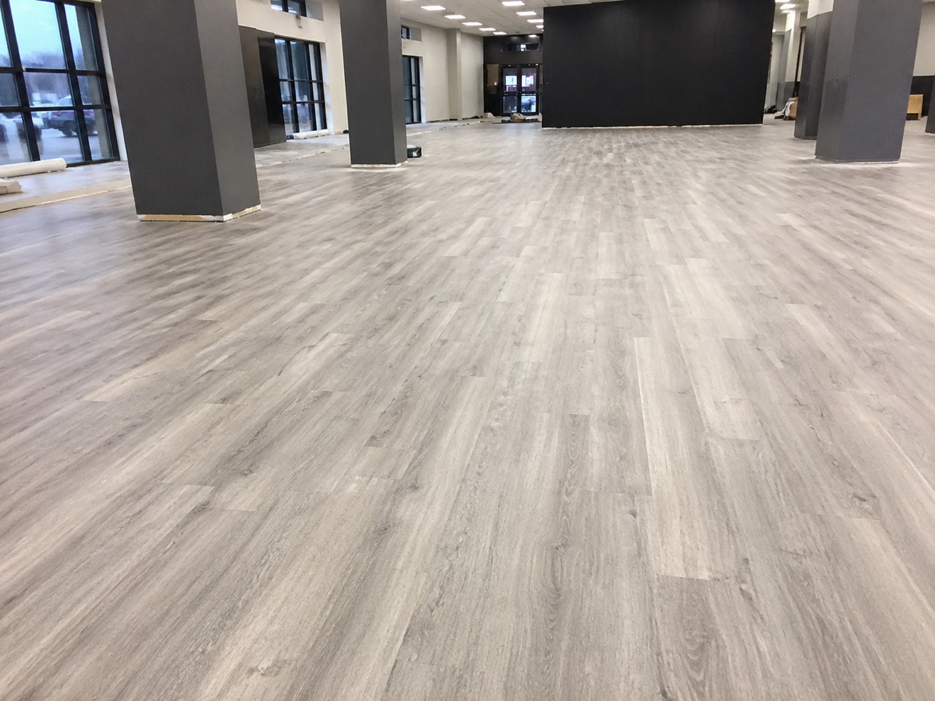 Finished gray wood-look glue-down LVP across a large commercial interior