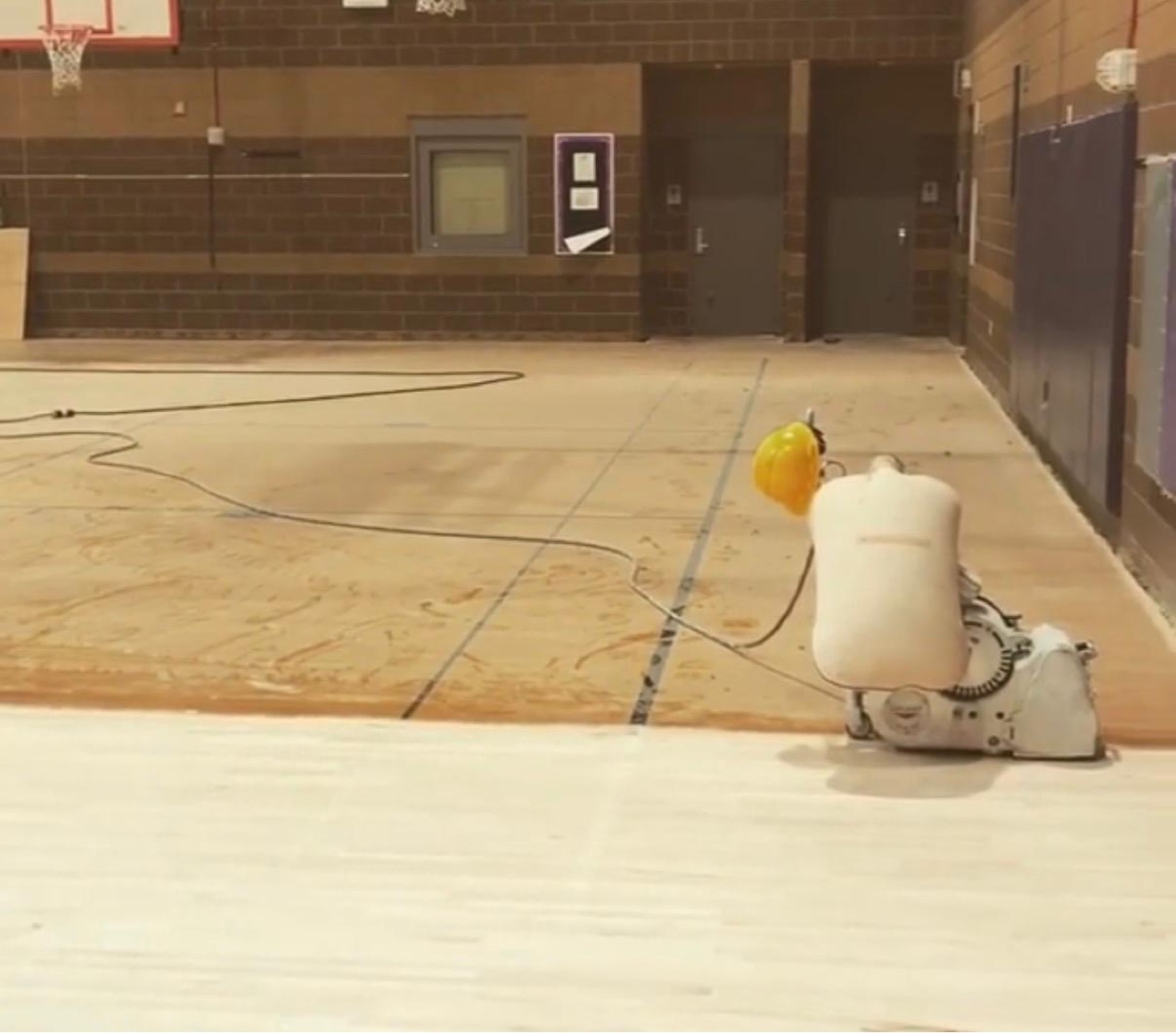 Floor sander refinishing a commercial wood sports court